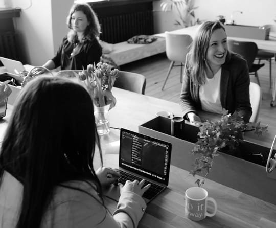 three people coding on laptops at a table